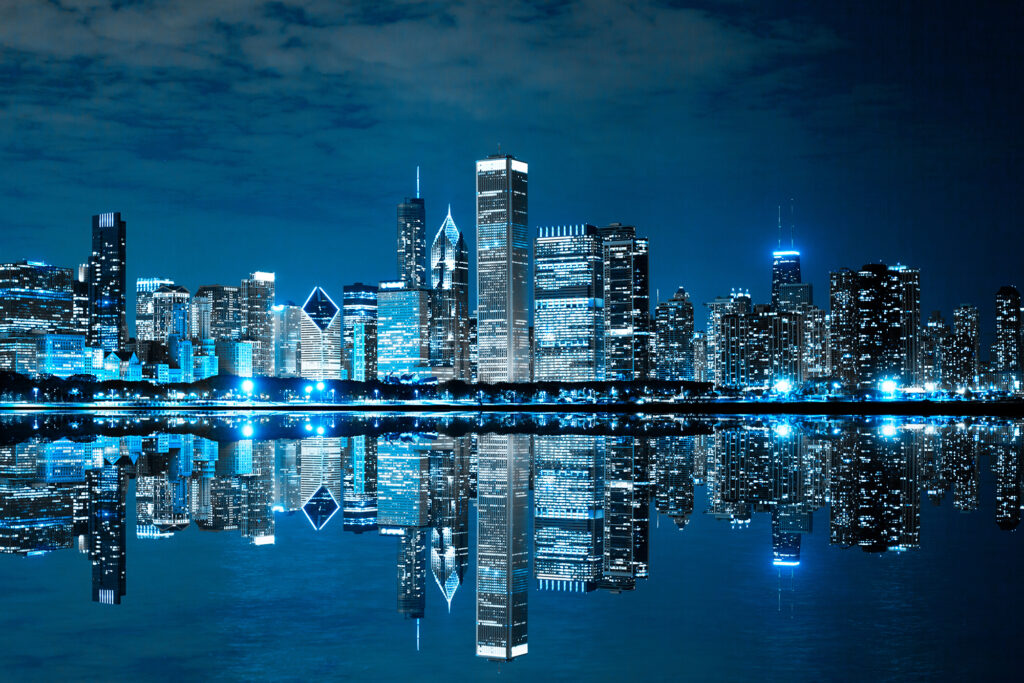 a cityscape is lit up at night and reflecting in the water.