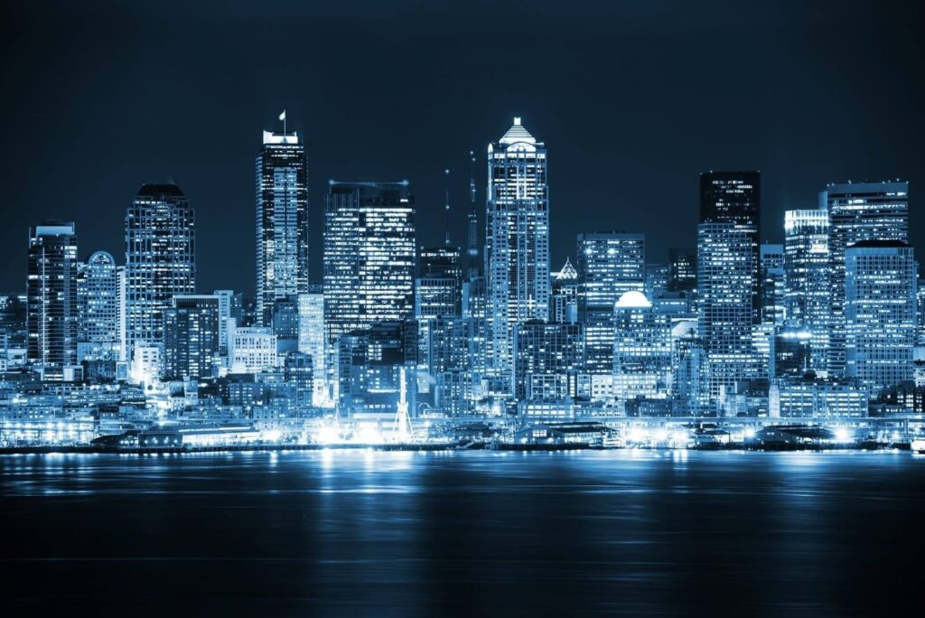 a city skyline at night with lights reflecting off the water.