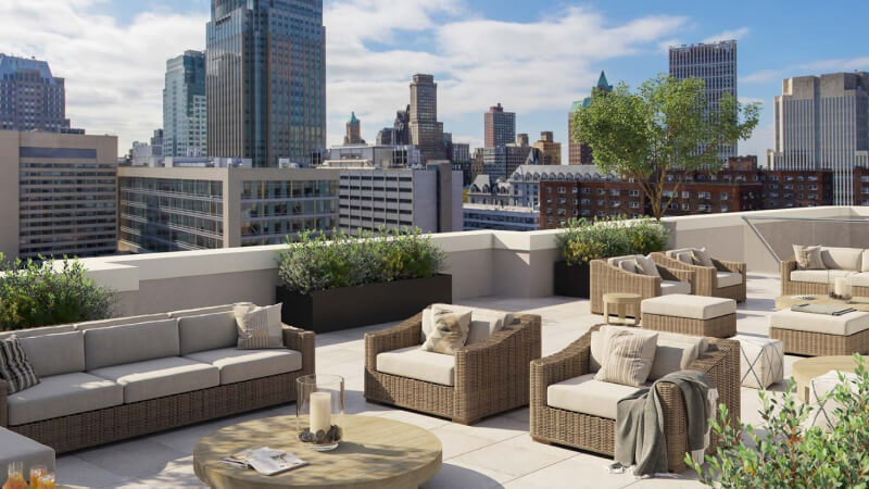 a patio with couches, tables, chairs and a view of the city.
